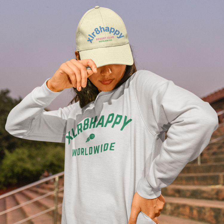 Xlr8happy cap in yellow with periwinkle letters worn by brown hair girl looking down. Xlr8happy shows how to be happy